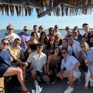 A group of people pose for a photo while on a tiki boat for a corporate event in Long Island, NY